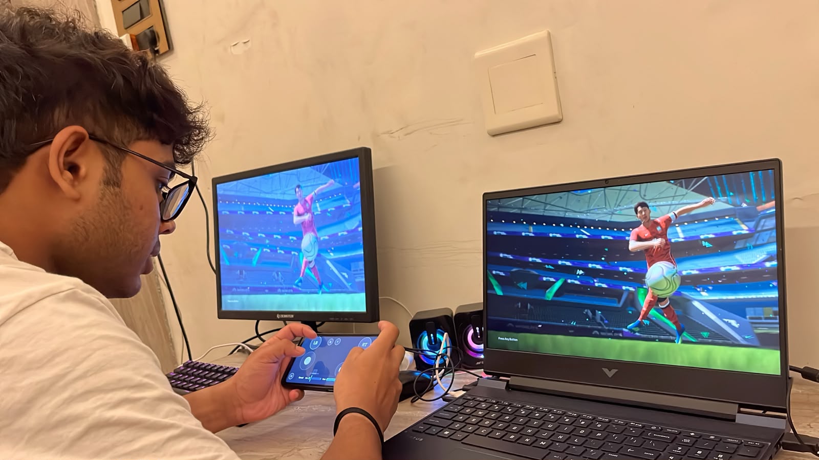 An early tester playing EA FC 26 on a gaming laptop while holding a phone running the droidOSS controller layout